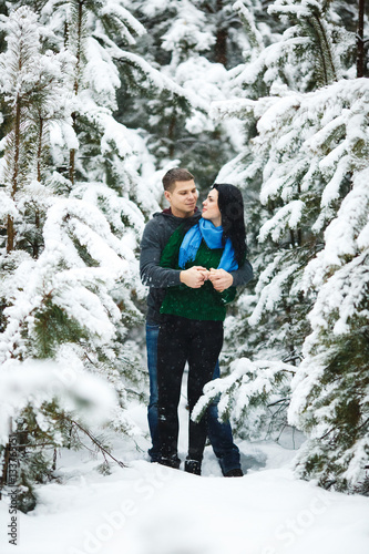 happy loving couple walking in snowy winter forest, spending christmas vacation together. Lifestyle capture.