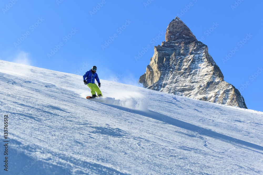 Male snowboarder on the slope with Matterhorn mountain peak on background