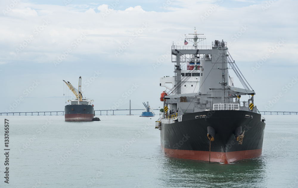 A landscape image of a cargo ship sailing past the Penang Bridge. A landscape image of a cargo ship sailing past the Penang Bridge.