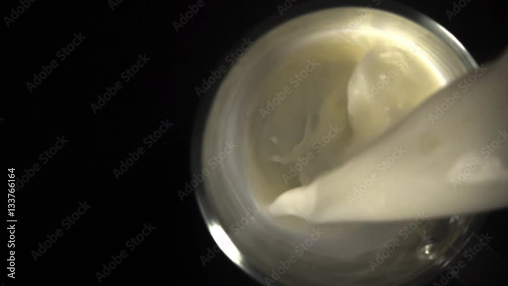 Pouring milk in the glass cup on black background Pouring milk in the glass cup on black background