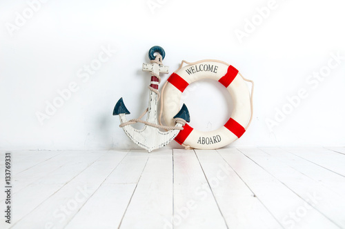 Anchor and life buoy on a white wooden floor photo