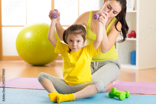 Woman helps child doing fit...