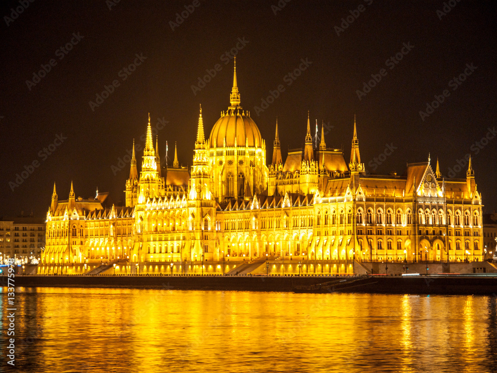 Fototapeta premium Night view of illuminated historical building of Hungarian Parliament, aka Orszaghaz, with typical symmetrical architecture and central dome on Danube River embankment in Budapest, Hungary, Europe. It