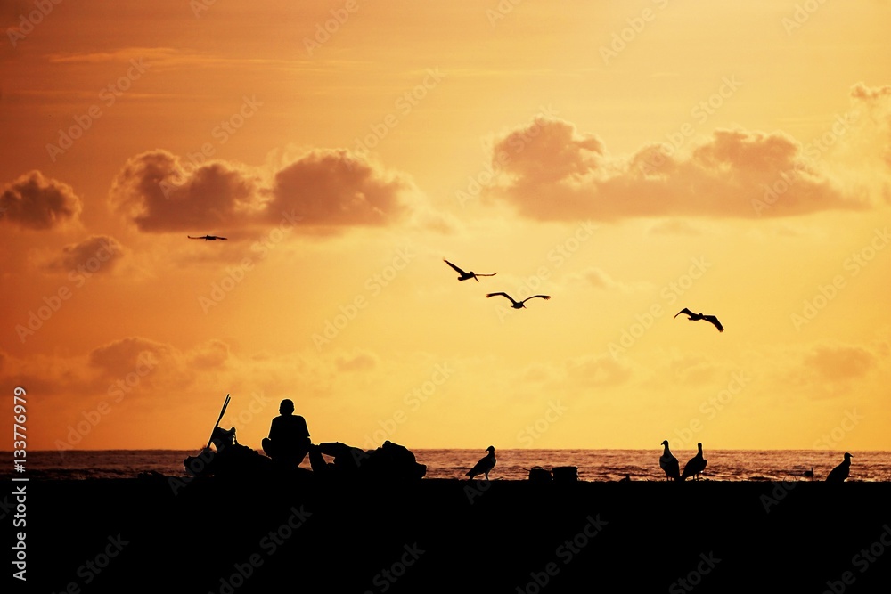 fisherman silouhette on the beach at sunset