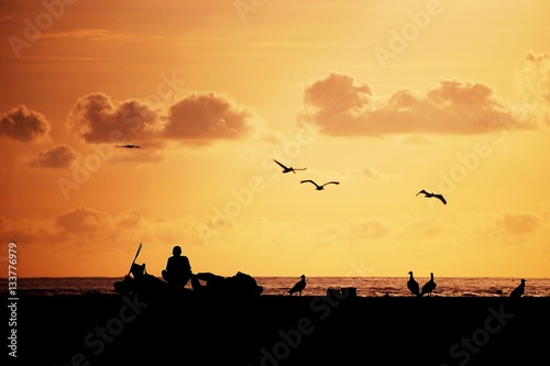 fisherman silouhette on the beach at sunset