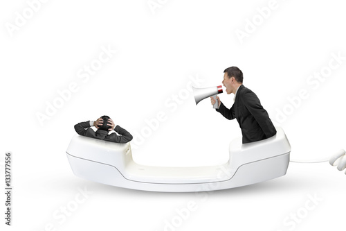 Telephone handset with businessman using speaker yelling at anot photo