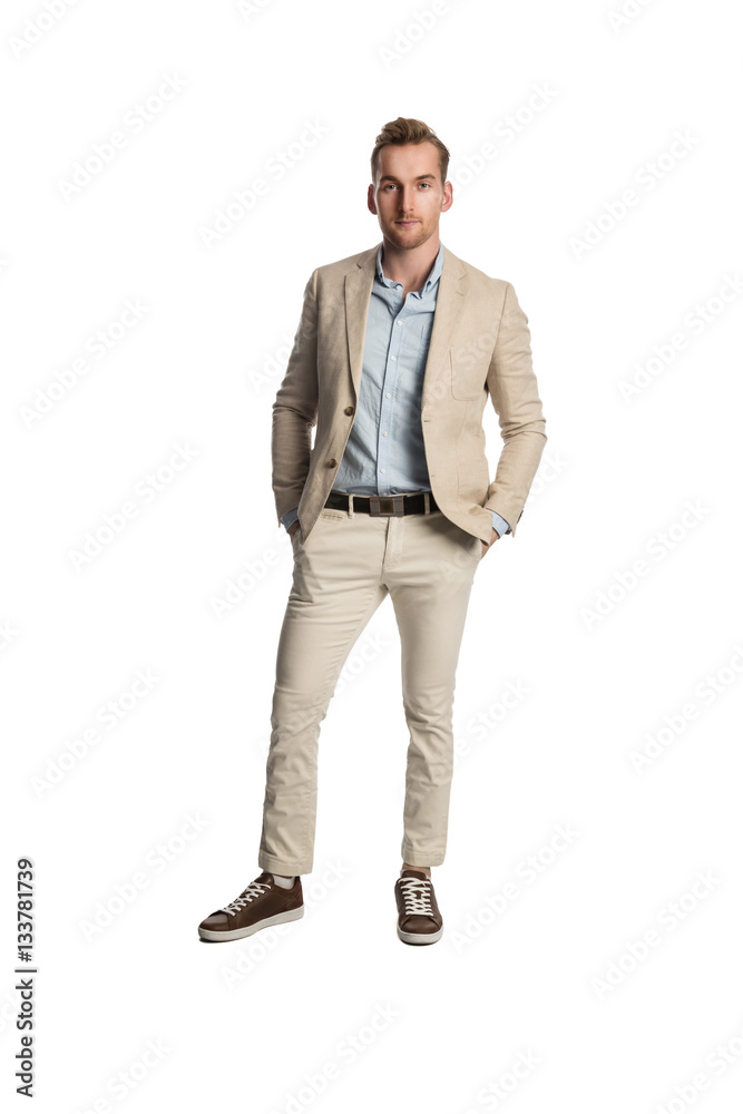 Attractive blonde man standing against a white background wearing a khaki bright suit with a blue shirt, feeling calm and relaxed. Attractive blonde man standing against a white background wearing a khaki bright suit with a blue shirt, feeling calm and relaxed.