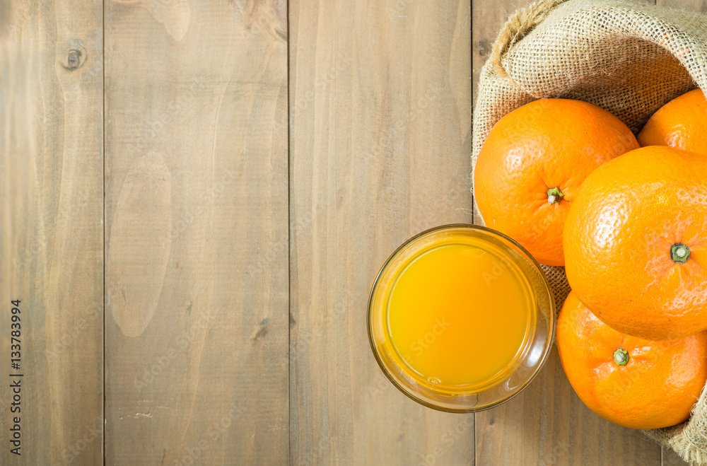 orange juice in glass and oranges in gunny sack on wood table top with copy  space, top view Stock Photo