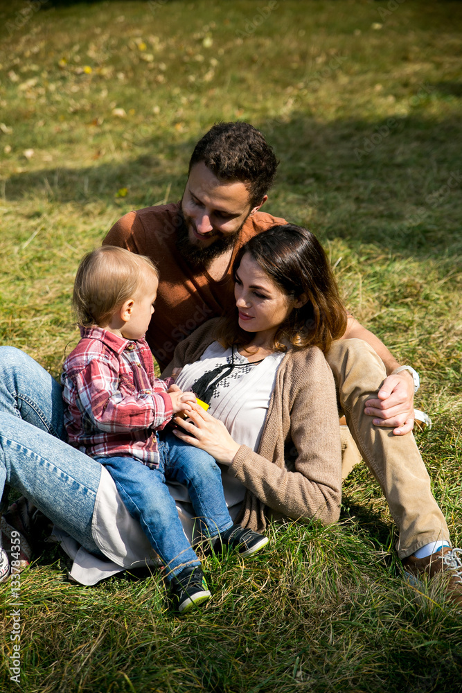 Happy joyful young family with child. Father, mother and little boy having fun outdoors in orchard garden, playing together in summer park. Mom, Dad, baby laughing and enjoying nature