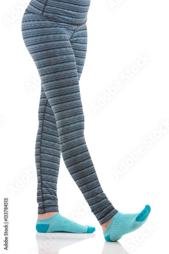 Woman legs while stretching exercise wearing colourful blue and grey striped sports pants and blue socks