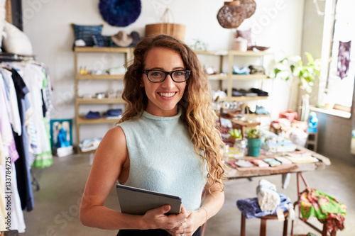 Female business owner holding tablet computer in clothes shop