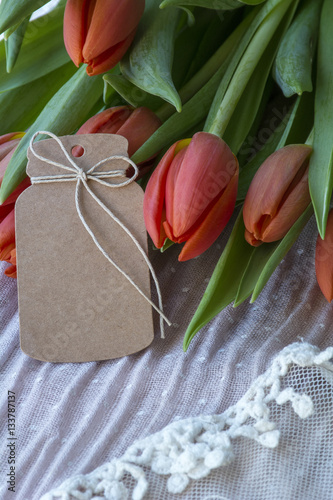 Fototapeta Naklejka Na Ścianę i Meble -  Bouquet of red tulips with brown card on light pink background