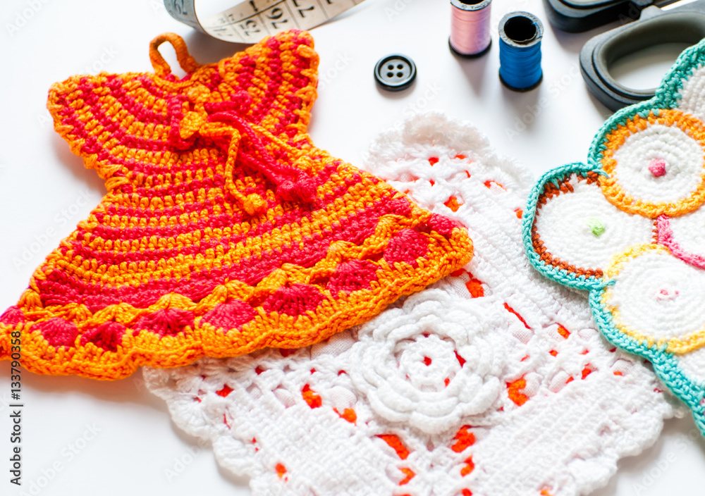 hand knit pot holders next to scissors, tape measure and colored spools