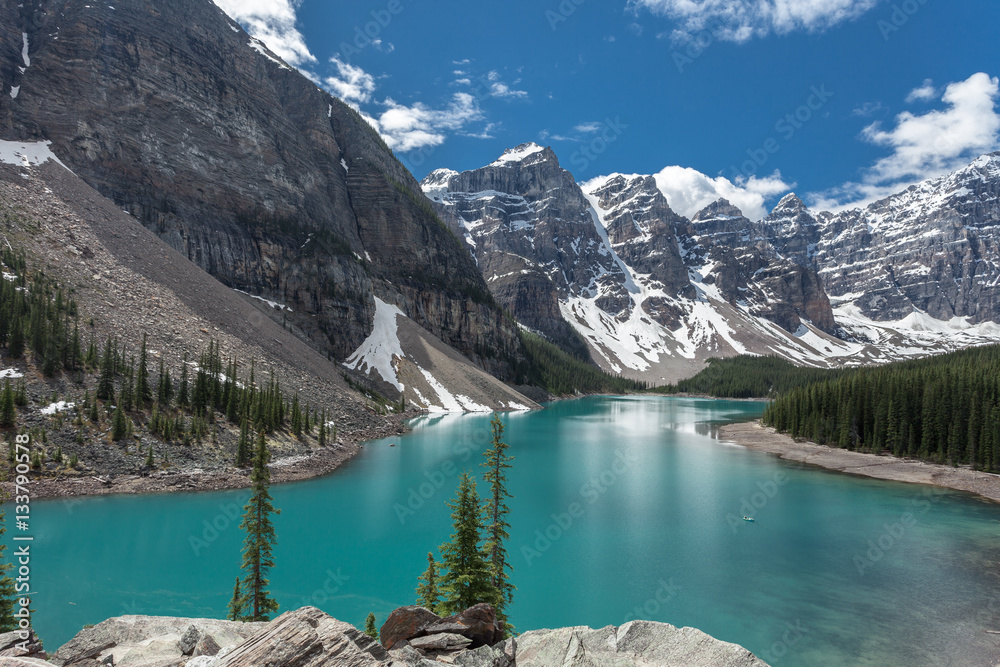 Moraine lake in Banff National Park, Canadian Rockies, Canada. Sunny summer day with amazing blue sky. Majestic mountains in the background. Clear turquoise blue water.