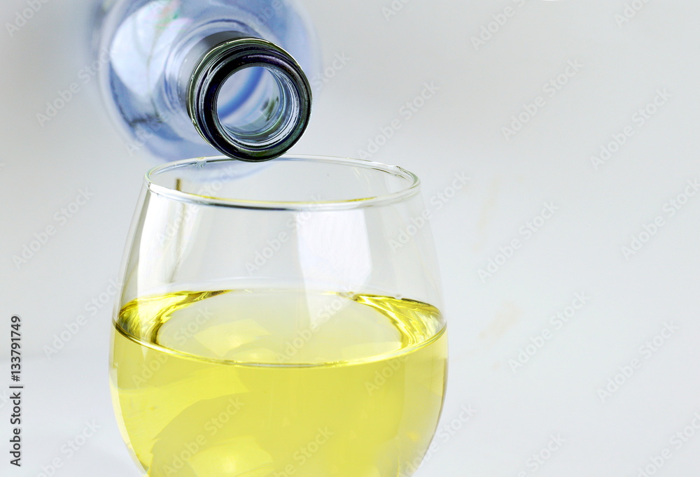 Bottle of white wine glass being poured in a glass isolated Bottle of white wine glass being poured in a glass isolated
