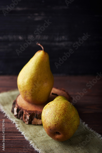 Two fresh green pears on a rustic background with napkin. Vertical shot