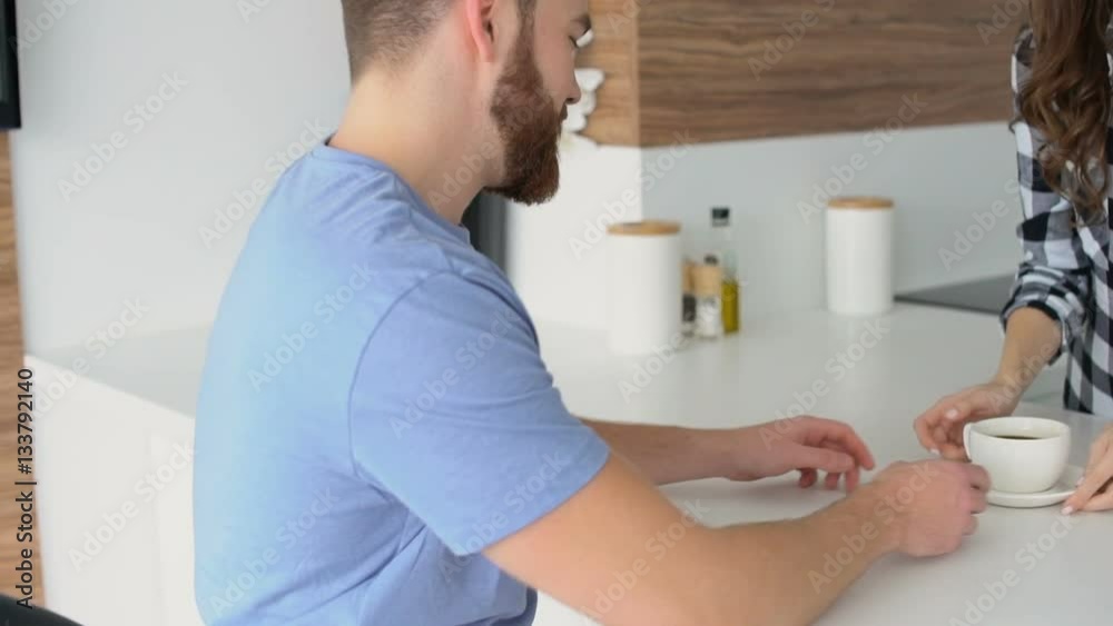 Young smiling couple dinking coffee together in the kitchen and talking Young smiling couple dinking coffee together in the kitchen and talking