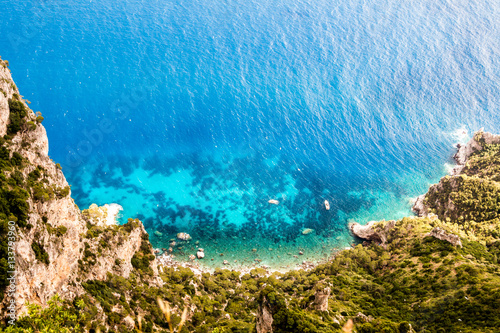 Top down view on a blue clean turquoise lagoon with a boat. Lonely motor boat is floating on a blue lagoon waters. High cliffs surround lagoon from the ocean. © divampo