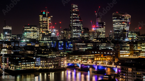 Modern big city tall skyscrapers in the industrial business city at night. Capital of finances City of London at night. Long and curvy lights reflections in the river Thames. © divampo