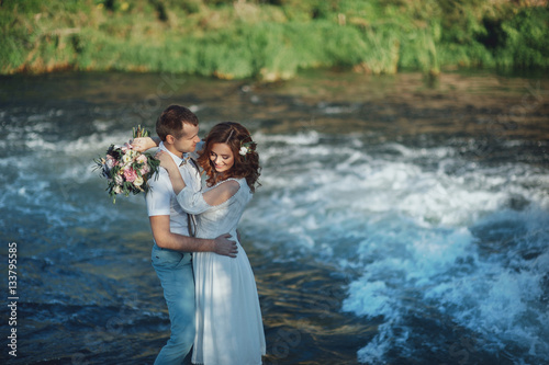 the bride and groom on the background of a mountain stream