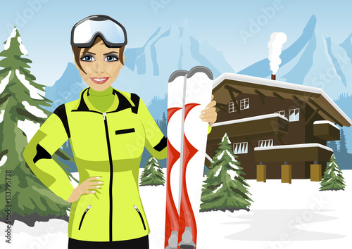 female mountain skier standing in front of chalet in winter ski resort