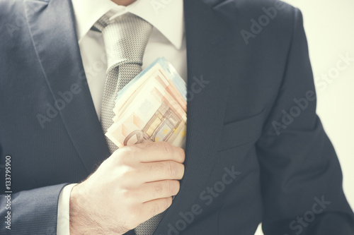 Businessman putting money in his pocket photo
