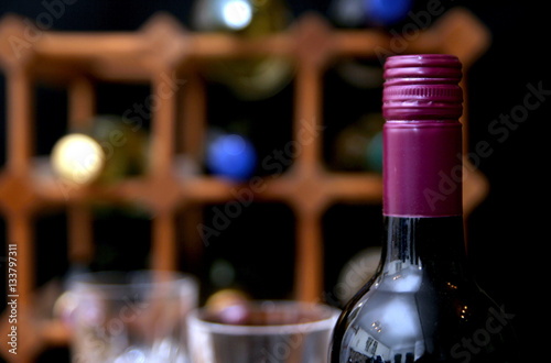 Closeup of burgundy screw top wine bottle with wine rack and win