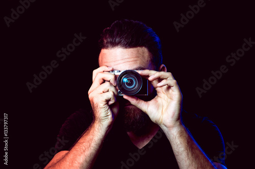 Mann mit Kamera vor schwarzem Hintergrund