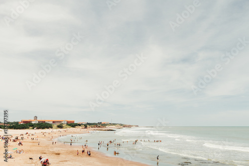 фотографія Beach with bathers in the sea and traditional hotel in the backg