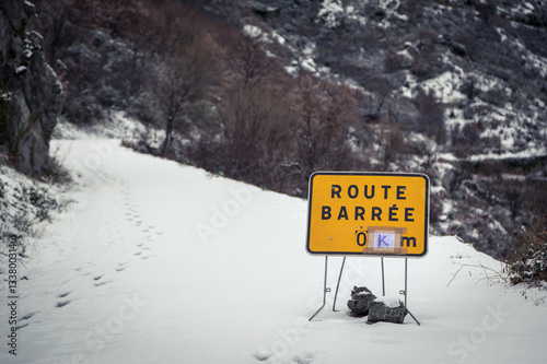 Road blocked sign on snow covered mountain road in Corsica