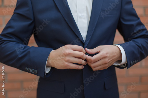 Making business look, close-up of man buttoning his jacket