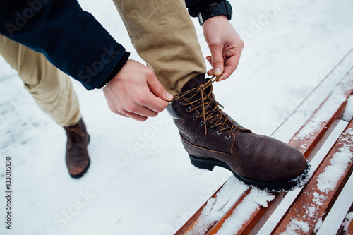 Shoelaces of boots. Man tying shoelaces on winter boots in winter day