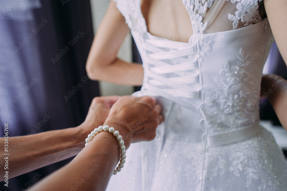 bridesmaid tying bow on wedding dress
