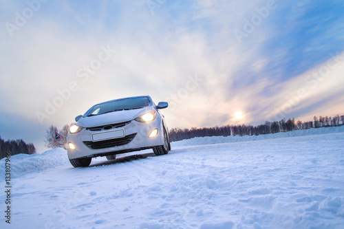 White car in a winter field on the road