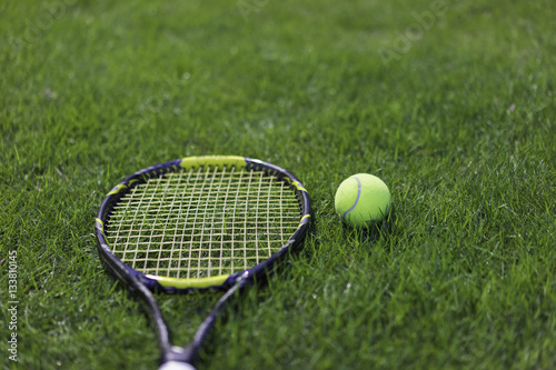 Tennis ball with racket on wet grass after raining