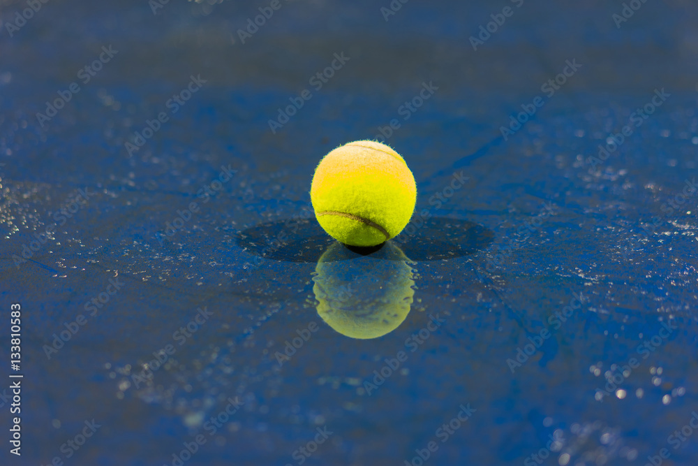 Tennis ball with reflection on ground after raining