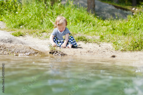 Fototapeta Naklejka Na Ścianę i Meble -  Little girl playing on the river bank