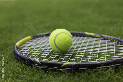 Tennis ball and racket on green grass background © Hanoi Photography
