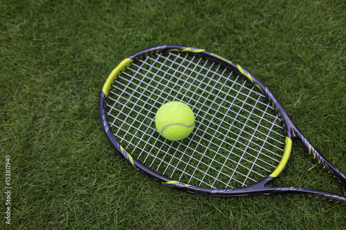 Tennis ball and racket on green grass background © Hanoi Photography
