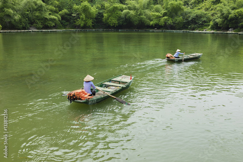 Vietnamese woman rowing boat on river