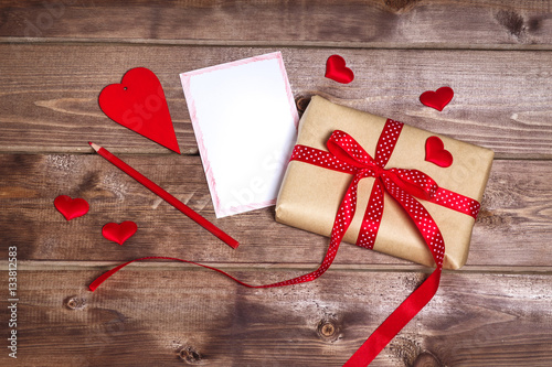Wrapped vintage gift box with red ribbon bow and gift card aover the wooden table can use on valentine day mother day or celebrate love day . photo