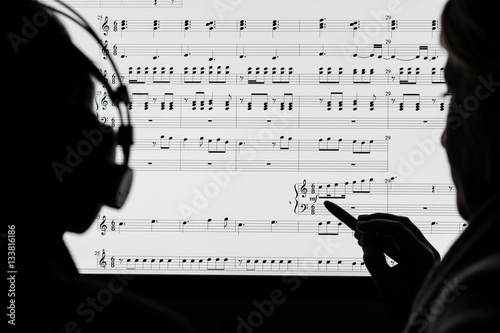 Two people working on a musical score using computer notation software. Not a real score, notes randomly drawn in by the photographer. photo