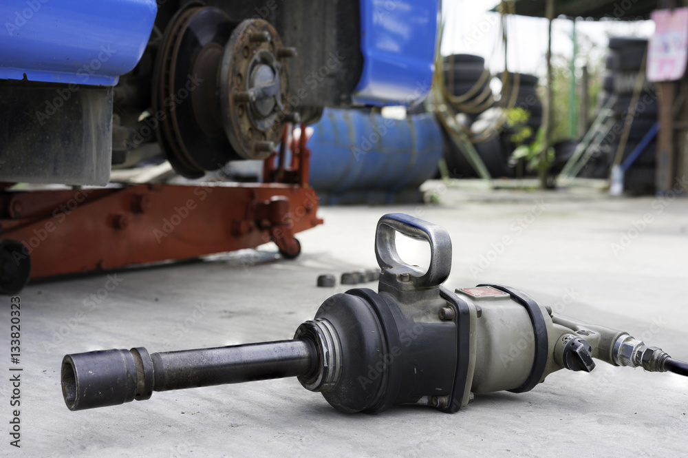 Wrench machine against car wich has tire needs to fix on background Wrench machine against car wich has tire needs to fix on background