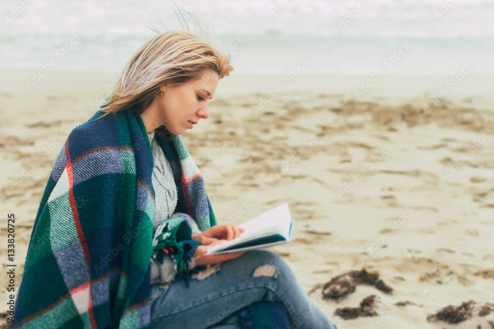 A girl reads a book on the beach