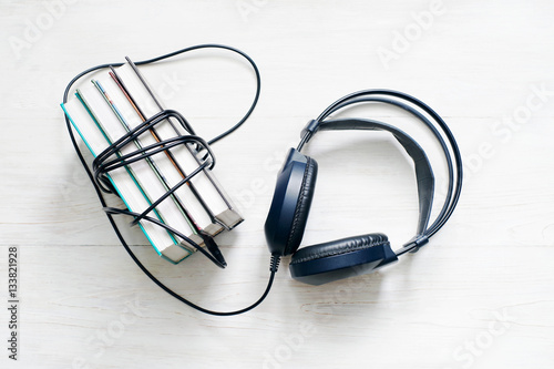 Books and headphones on wooden white surface. Concept of listening to audiobooks.