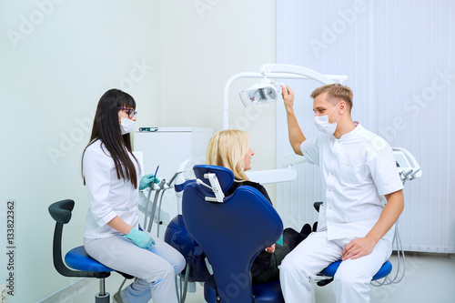 The patient, dentist and assistant in office of a dental clinic.
