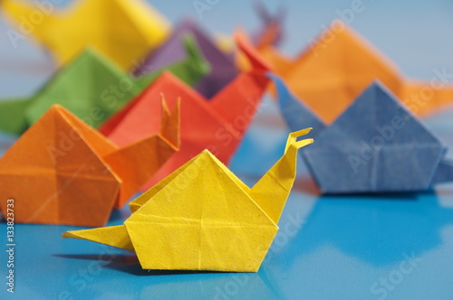 Paper origami snail isolated on a colorful background