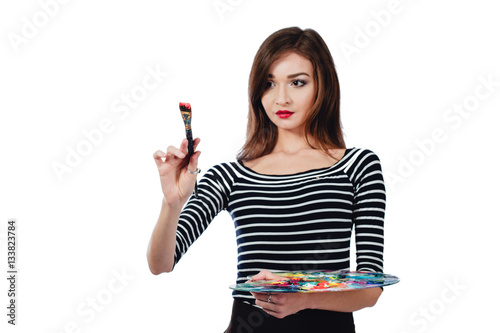 Cute beautiful girl artist holding a palette and  brush in the process draws inspiration. White background  isolated.
