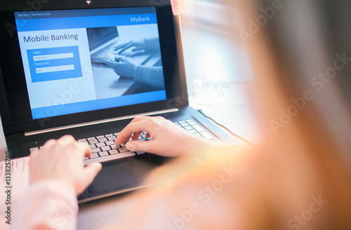 Close up of woman hands using on line banking on laptop computer logging in to a bank account typing password. Business, financial and secure payment concept.  © NinaMalyna