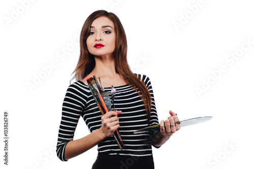 Cute beautiful girl artist holding a palette and brush in the process draws inspiration. White background  isolated.